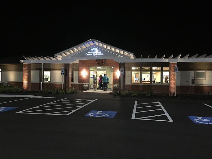 Color photo taken at night of front entrance to New England Cancer Specialists, West Kennebunk, Maine